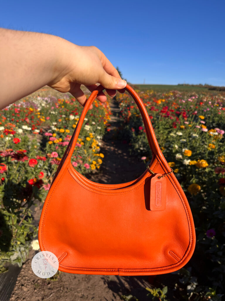 vintage coach Ergo mini bag in tangerine orange leather in front of flower field